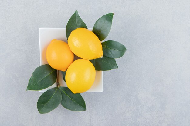 Limones amarillos frescos en un plato blanco.