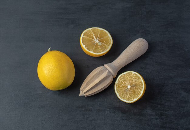 Limones amarillos frescos en rodajas y enteros con un escariador de madera.