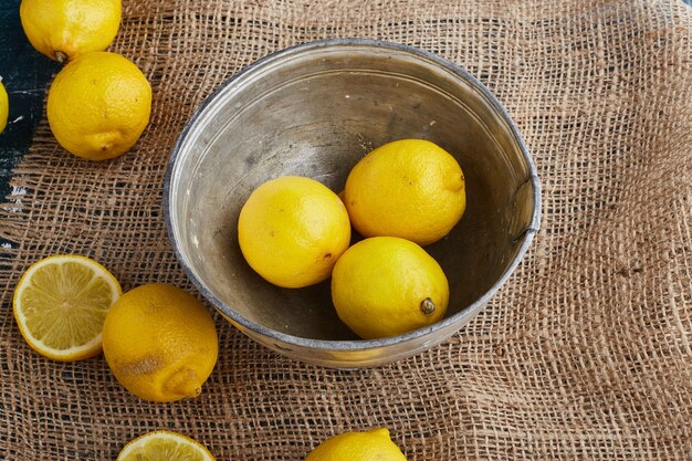 Limones amarillos en un recipiente metálico.
