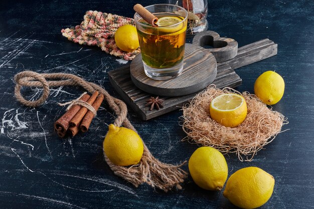 Limones amarillos sobre una superficie negra con una copa de vino brillante.