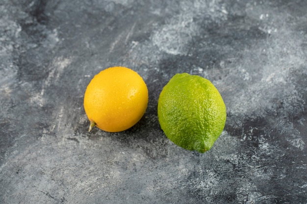 Limones amarillos y verdes sobre una superficie de mármol.