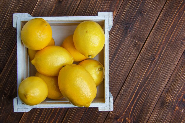 Los limones en una caja de madera plana yacían sobre una mesa de madera