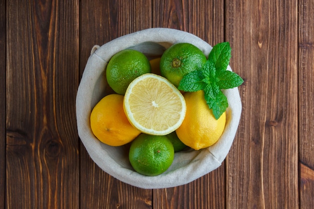 Limones en una canasta sobre una superficie de madera. vista superior.