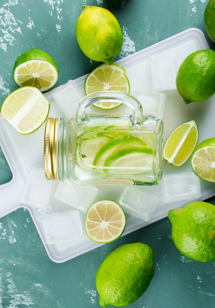 Limones con cubitos de hielo, limonada sobre yeso y tabla para cortar,