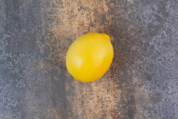 Un limones enteros en el espacio de mármol.