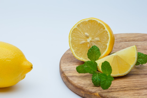 Limones frescos con hojas en blanco y tabla de cortar