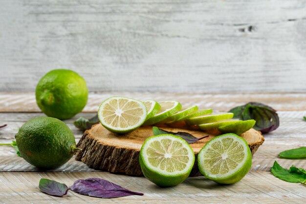 Limones con hojas de albahaca, tabla de cortar en madera y grungy,