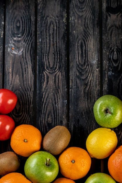 Foto gratuita limones, manzanas, kiwi y mandarinas en una mesa de madera