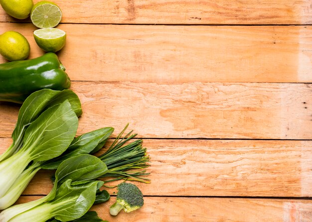 Limones Pimientos; brócoli; cebollino y bokchoy sobre tabla de madera