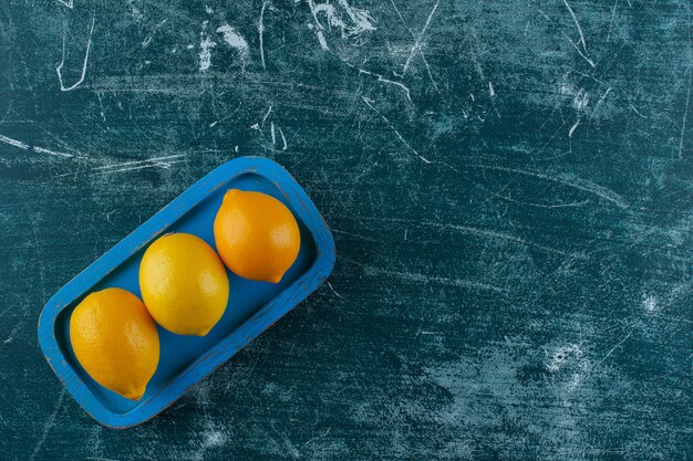 Limones en una placa de madera, sobre la mesa de mármol.