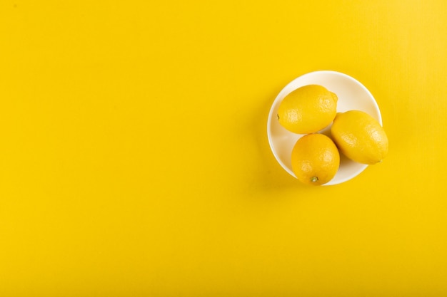 Limones en un plato blanco sobre amarillo
