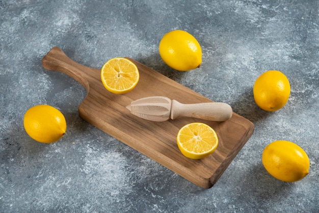 Limones en rodajas y enteros con escariador de madera.