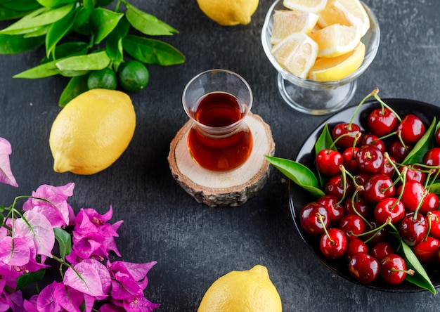 Limones con rodajas, hojas, flores y un vaso de té.