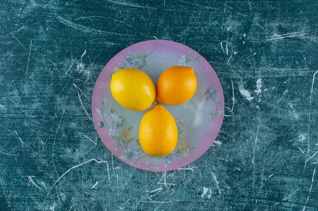 Limones sabrosos en plato, sobre la mesa de mármol.