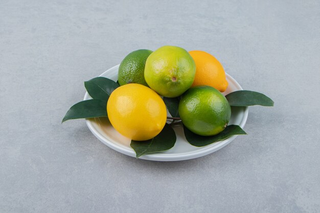 Limones verdes y amarillos en un plato blanco.