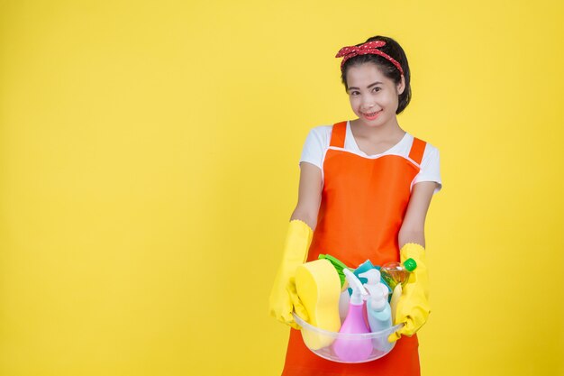 Limpieza Una mujer hermosa con un dispositivo de limpieza en un amarillo.