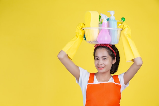 Limpieza Una mujer hermosa con un dispositivo de limpieza en un amarillo.