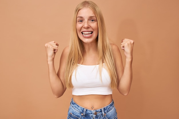 Foto gratuita linda adolescente de moda con cabello rubio viste jeans y top blanco