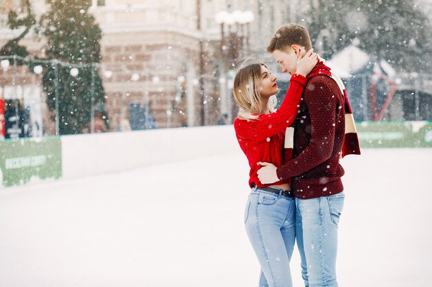 Linda y amorosa pareja en un suéter rojo en una ciudad de invierno