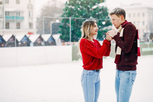 Linda y amorosa pareja en un suéter rojo en una ciudad de invierno