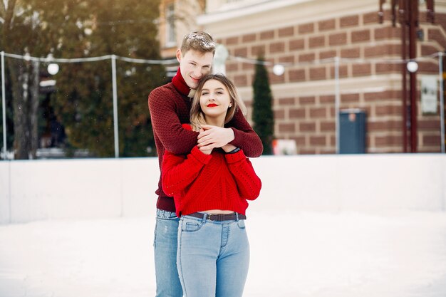 Linda y amorosa pareja en un suéter rojo en una ciudad de invierno