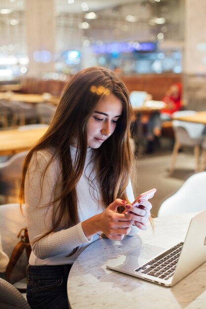 Linda y bastante joven en smartphone en café