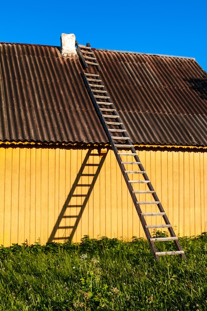 Linda casa rural amarilla con escaleras de madera en campo.