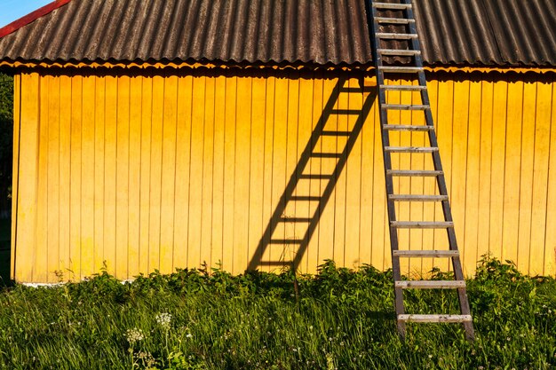 Linda casa rural amarilla con escaleras de madera en campo.