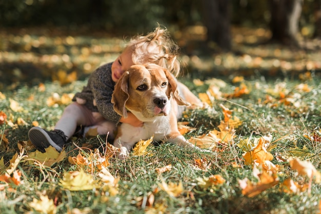 Linda chica abrazando a su mascota en la hierba