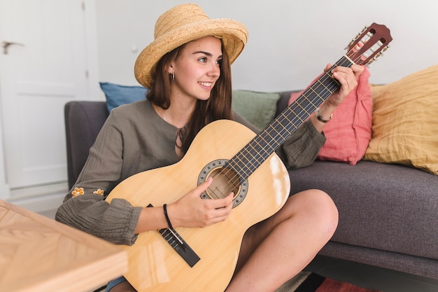 Linda chica adolescente tocando la guitarra en casa