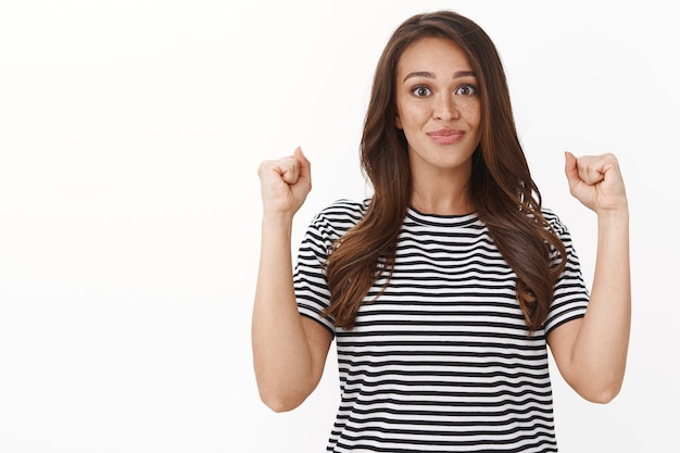 La linda chica afortunada empoderada cree que puede hacer cualquier cosa, aprieta los puños animada, sonriendo decidida, ambiciosa victoria, celebrando la victoria, triunfando alegre, sonriendo a la cámara feliz