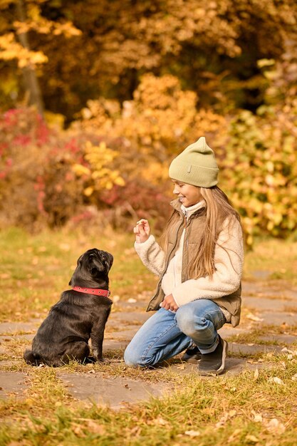 Una linda chica alimentando a su perro en el parque.