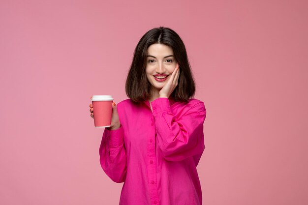 Linda chica bastante adorable chica en camisa rosa con lápiz labial rojo cubriendo la cara y sonriendo