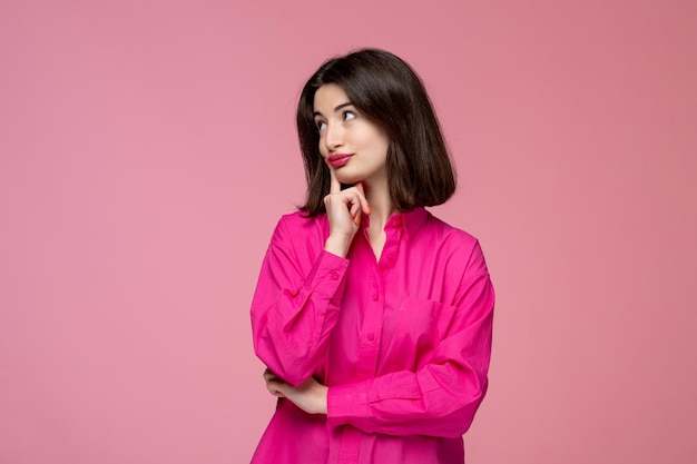 Linda chica bastante adorable chica en camisa rosa con lápiz labial rojo pensando y soñando