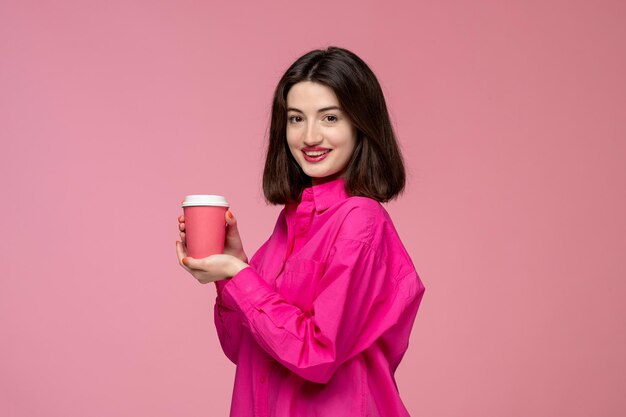 Linda chica bastante joven hermosa chica morena en camisa rosa sonriendo con taza de café