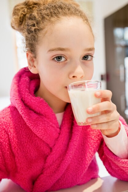 linda chica de beber leche en la cocina