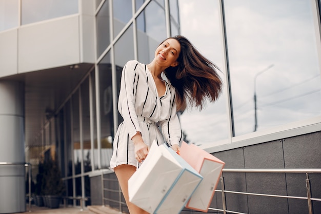 Linda chica con bolsa de compras en una ciudad