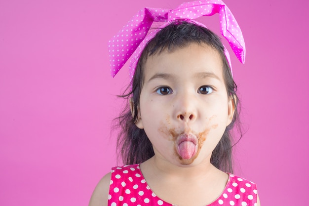 Una linda chica con una camisa a rayas rojas comiendo un chocolate con una boca sucia en el rosa.