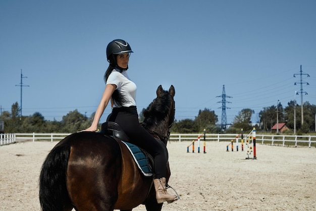 Linda chica en casco sentado en silla de montar a caballo al aire libre