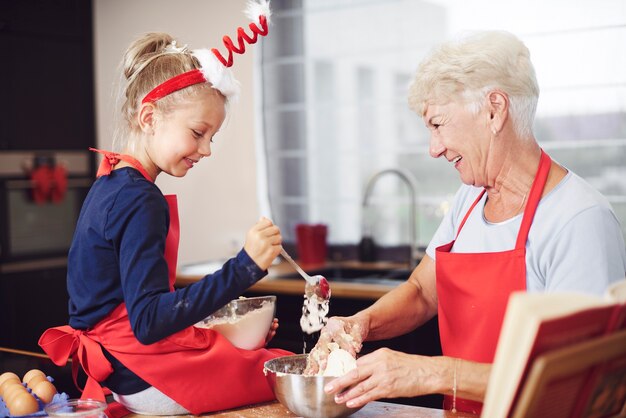 Linda chica cocinando con la ayuda de su abuela