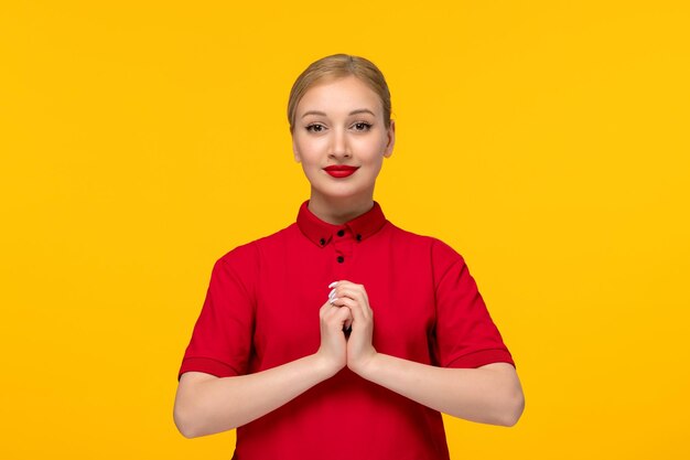 Linda chica del día de la camisa roja cogidos de la mano y sonriendo con una camisa roja sobre un fondo amarillo