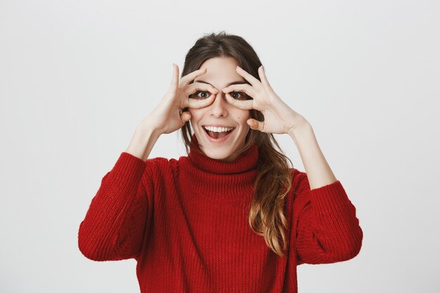 Linda chica divertida sonriendo, hacer vasos de manos