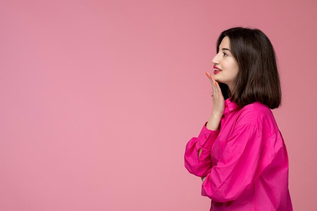 Linda chica encantadora dama adorable con lápiz labial rojo en camisa rosa soñando con algo