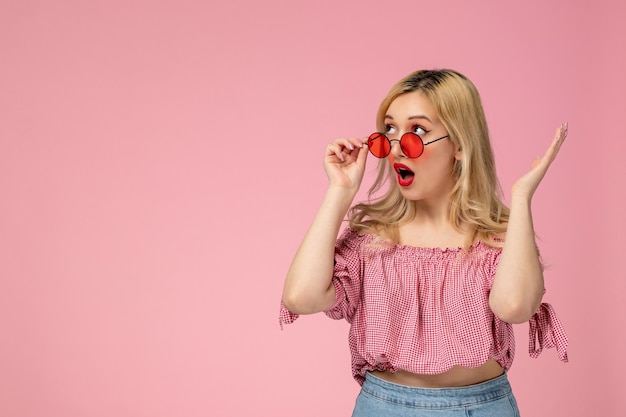 Foto gratuita linda chica encantadora jovencita con gafas rojas en blusa rosa sorprendida tocando gafas