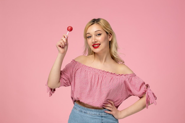 Linda chica encantadora jovencita con lápiz labial rojo en blusa rosa ondeando en el aire con la piruleta