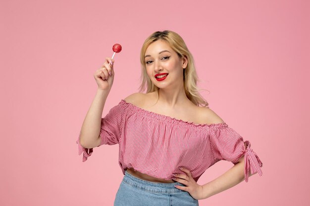 Linda chica encantadora jovencita con lápiz labial rojo en blusa rosa ondeando en el aire con la piruleta