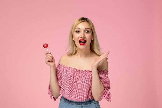 Linda chica encantadora jovencita con lápiz labial rojo en blusa rosa tan feliz por una piruleta de bayas