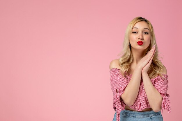 Linda chica encantadora señorita con lápiz labial rojo en blusa rosa enviando besos