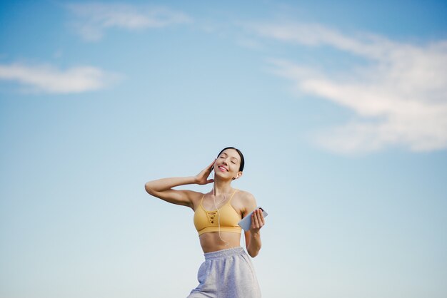 Linda chica con entrenamiento telefónico en cielo azul