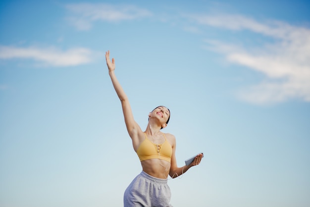 Linda chica con entrenamiento telefónico en cielo azul